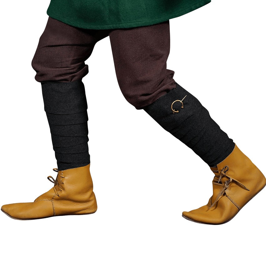 A close-up of a person's legs wearing dark brown and black leg warmers with a small gold ring detail, paired with tan leather slip-on boots against a white background.