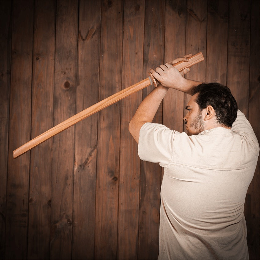 Man holding a training sword in a high guard.
