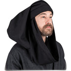 A man wearing a black medieval-style hood and matching dark textured tunic against a plain white background.