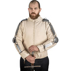 A bearded man wearing a medieval-style beige quilted jacket with metal chainmail sleeves and shoulder guards, holding a sword against a white background.