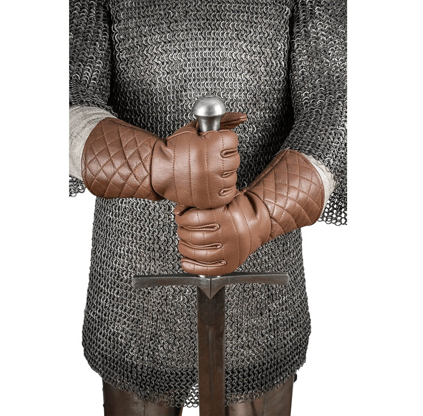 A person wearing medieval-style brown quilted leather gloves and a chainmail tunic, holding a sword with a silver pommel against a plain white background.
