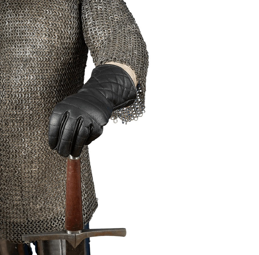 A close-up of a person wearing a chainmail shirt and a black quilted leather glove, holding the pommel of a sword against a plain white background.