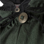 Close-up of a dark green textured fabric garment with black drawstrings and two round metallic coin-style closures, one larger engraved medallion on the front.
