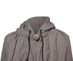 Close-up of a textured gray hooded garment with black drawstrings and a large round bronze button closure, shown against a plain white background.