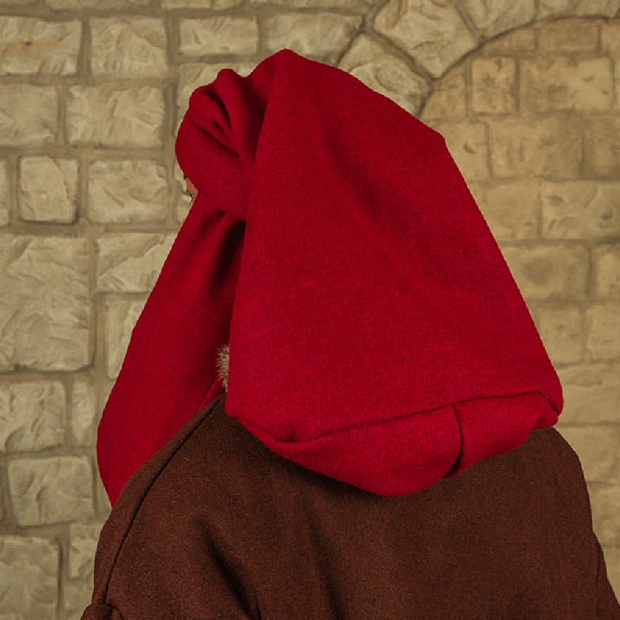 A person wearing a bright red hood or veil over a brown garment, photographed from the back against a light stone wall.